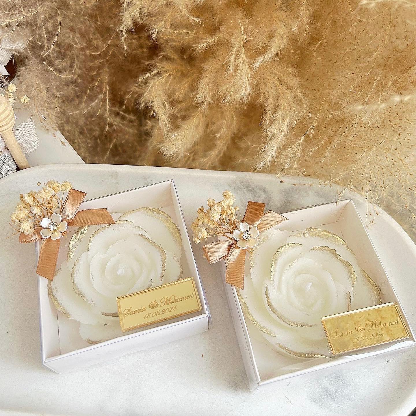 Cadeau invité mariage : bougie en forme de rose avec finitions dorées, fleurs séchées et étiquette personnalisée.