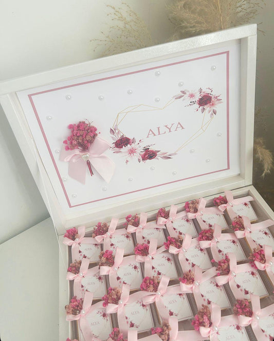 Cadeau invité baby shower : box chocolat thème rose, avec boîtes individuelles personnalisées et rubans satinés.