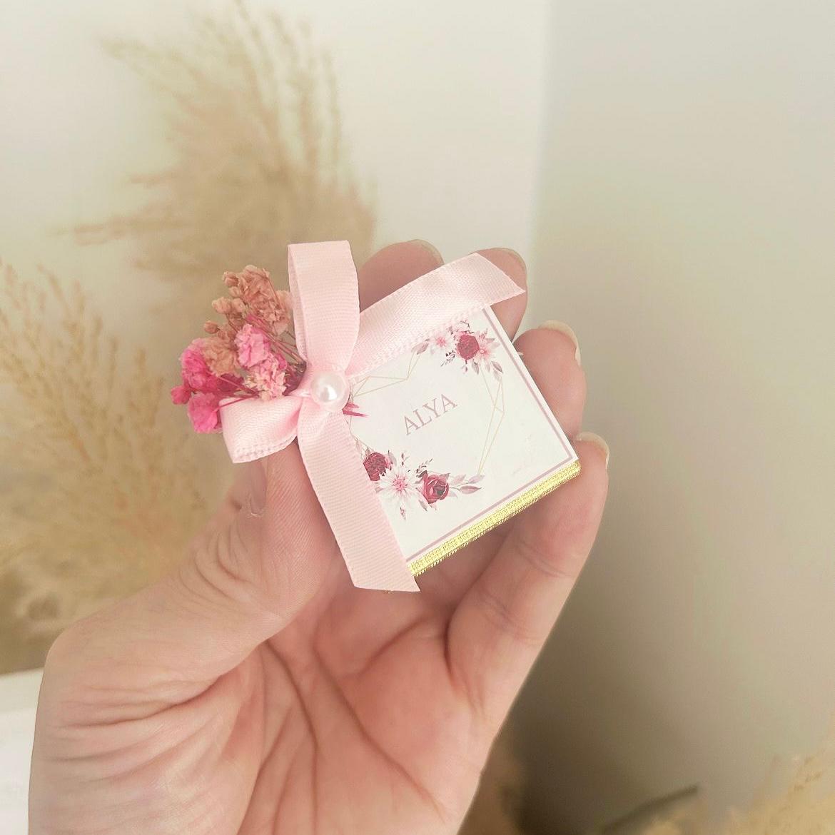 Cadeau invité baby shower : box chocolat thème rose, avec boîtes individuelles personnalisées et rubans satinés.