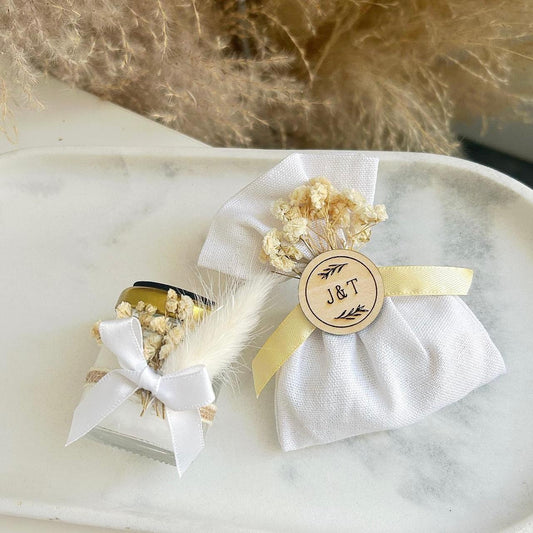 Cadeau invité : bourse de dragées rustique en tissu blanc avec fleurs séchées et médaillon en bois personnalisé.