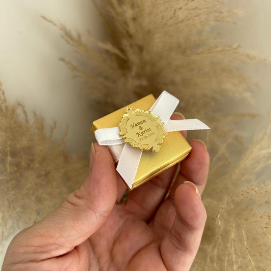 Boîte cadeau invité pour mariage, coloris or avec ruban blanc, personnalisée avec prénoms et date sur une médaille miroir