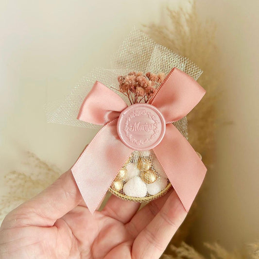Cadeau invité : sachet de dragées Rusia en tulle avec ruban satin rose, sceau décoratif et fleurs séchées.