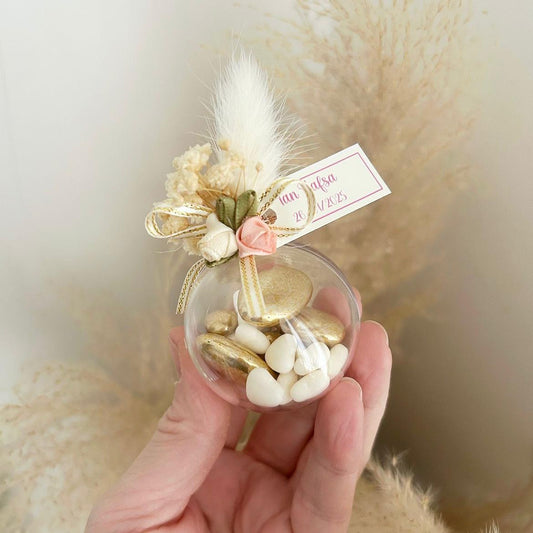 Cadeau invité : boule de dragées Vintage en plexi avec décoration bohème (plume, fleurs, rubans) et personnalisation.