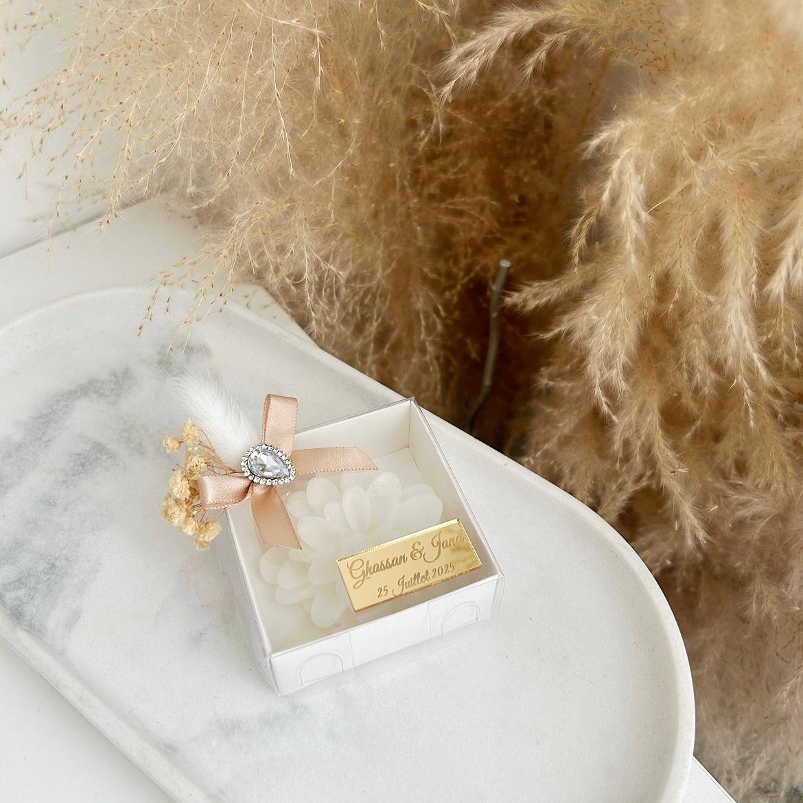 Bougie cadeau invité Diamant en coffret blanc, avec ruban beige, fleurs séchées et personnalisation sur plaque dorée.