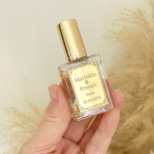 Cadeau invité : mini parfum Dubai avec capuchon doré, flacon transparent et étiquette personnalisée prénoms, ville et date.