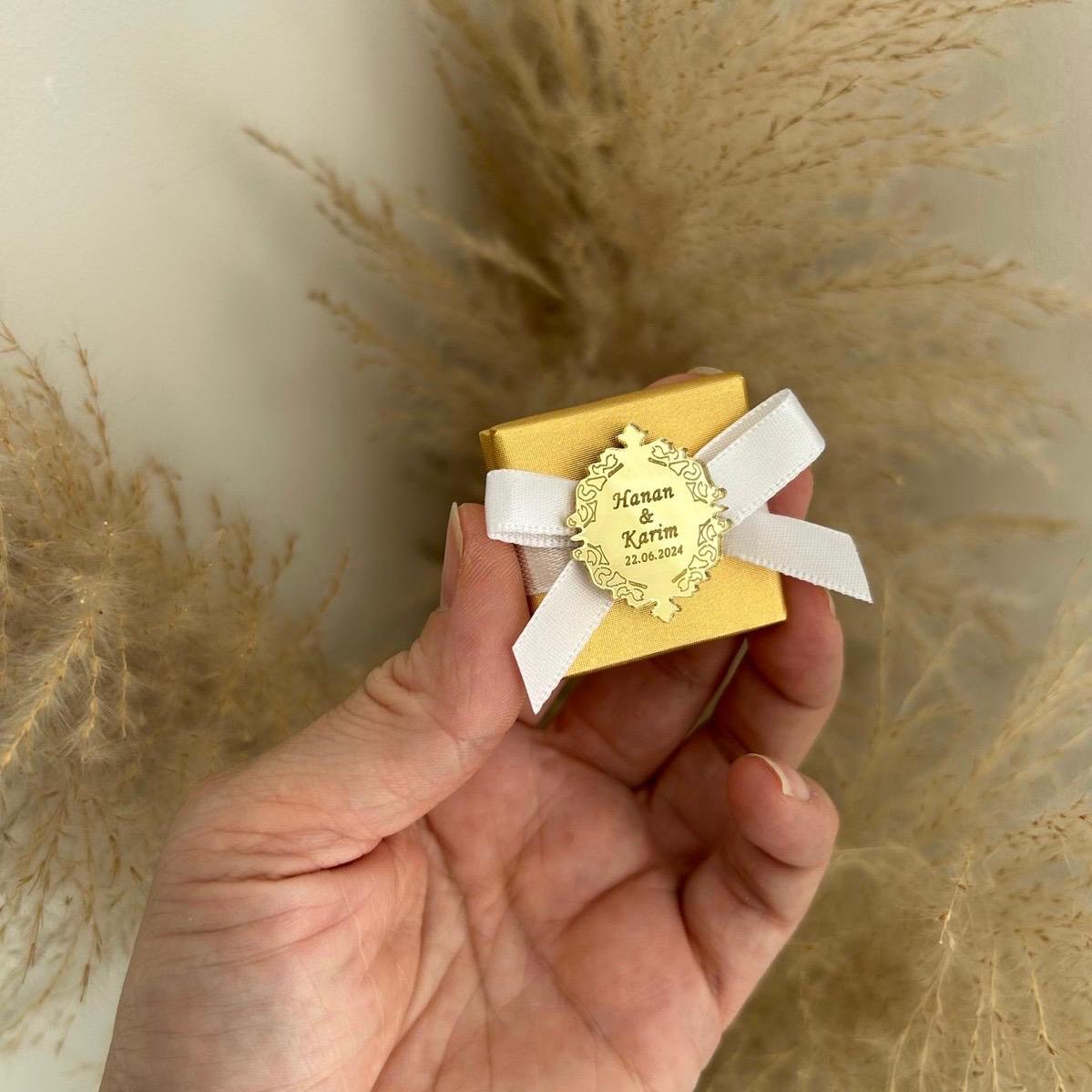 Boîte cadeau invité pour mariage, coloris or avec ruban blanc, personnalisée avec prénoms et date sur une médaille miroir