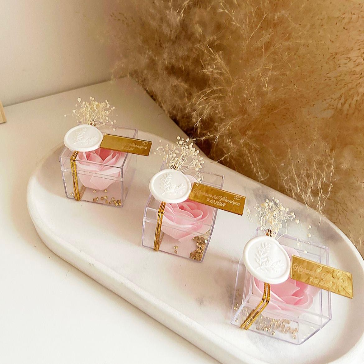 Cadeau invité : rose de savon Soélia rose en boîte plexi avec sceau blanc, fleurs séchées et plaque dorée personnalisée.